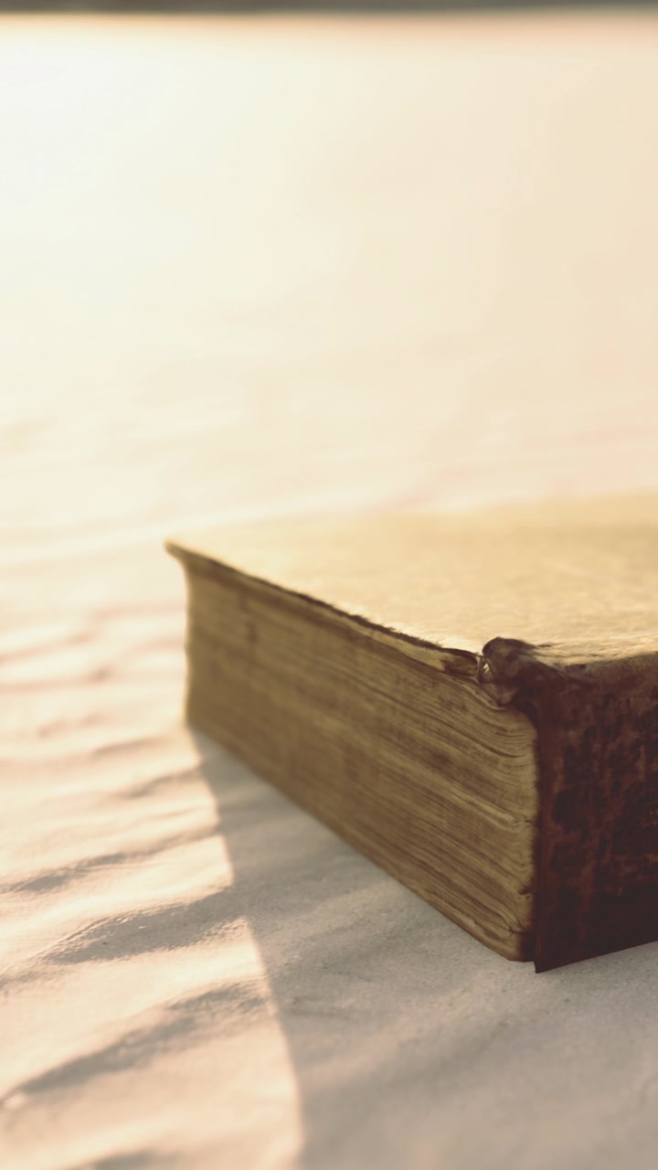 Un vecchio libro appoggiato sulla sabbia durante il tramonto in una tranquilla località balneare