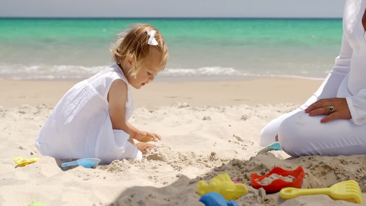 ein hübsches kleines mädchen zahlt im strandsand