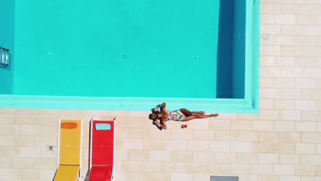 woman in swimsuit lying and sunbathing at pool edge