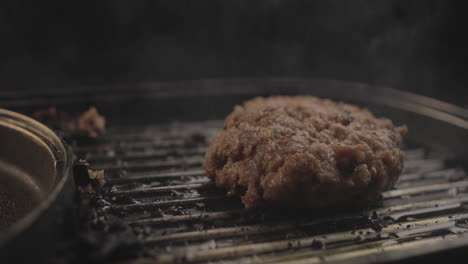 carne cruda o hamburguesa de pollo en la parrilla se está preparando para un delicioso sándwich de hamburguesa y volteado, con un fondo negro y la luz simple configurado disparado en crudo 4k