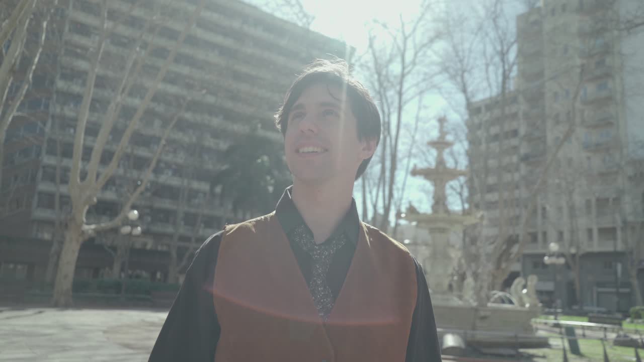 Arc Shot of young business man looking at the sky and nodding in a public square 4k shot