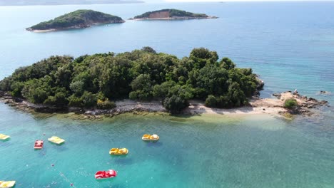 drone view in albania zooming out three small green islands on a clear blue ocean, sunny day in ksamil