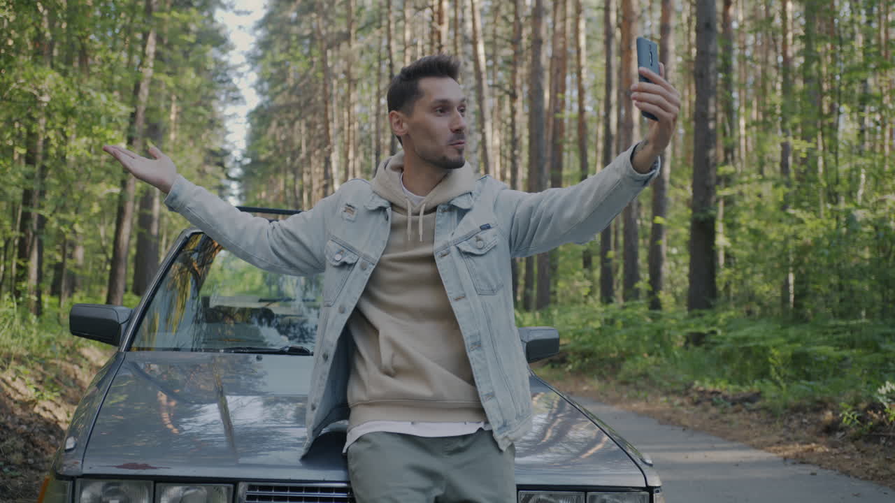 Man taking a selfie by a car in the forest