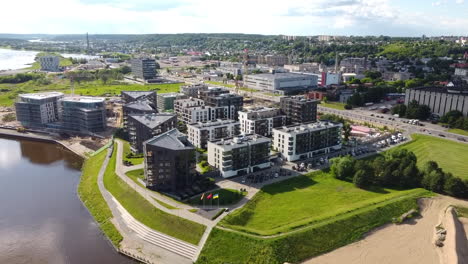 Luftaufnahme,-Moderner-Nachhaltiger-Wohnkomplex-Am-Flussufer-In-Kaunas,-Litauen-An-Einem-Sommertag,-Drohnenaufnahme-60fps