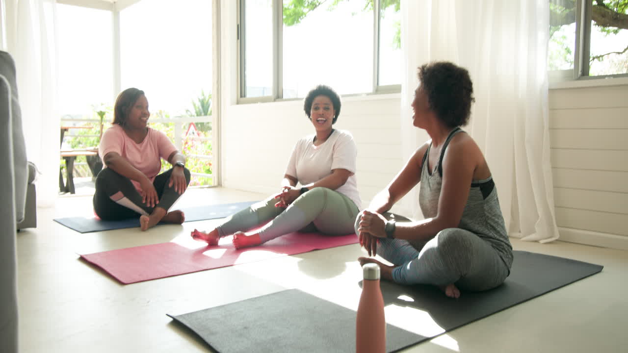 Relaxing on yoga mats, women talking and laughing together at home