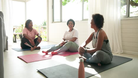relaxing on yoga mats, women talking and laughing together at home