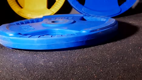 blue gym weight plate dropped on rubber floor in commercial gym