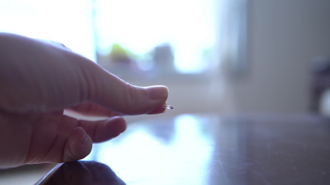 una mujer sosteniendo una garra de gato que se encontró en la casa, en el fondo en el fondo hay una gran ventana de la sala de estar