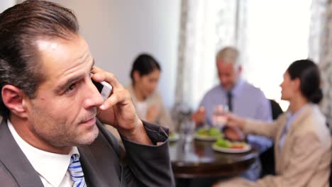 Businessman-talking-on-phone-at-business-lunch