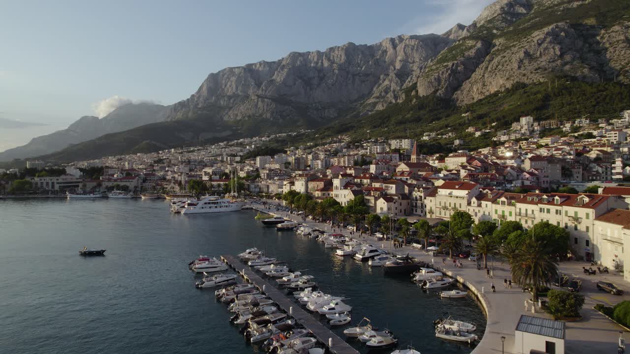 크로아티아 마카르스카 의 마리나 근처 의 해안 산책로 를 고 있는 관광객 들