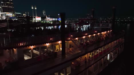 Aerial-view-close-to-a-steamboat-on-the-Ohio-river,-night-in-Cincinnati,-USA