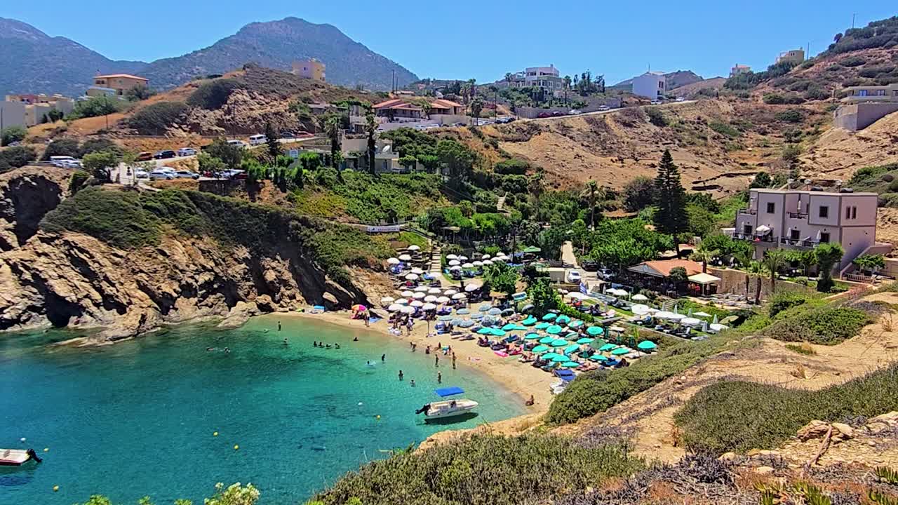 Vista panoramica della spiaggia di Karavostasi in Grecia con mare turchese, costa di ciottoli, onde leggere e un'atmosfera estiva tranquilla che crea filmati di viaggio costieri rilassanti e naturali.
