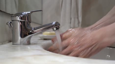 old man's hand's are washed on tap water with soap, then rinsed and wiped on a white cloth towel - side view static close-up shot 4k