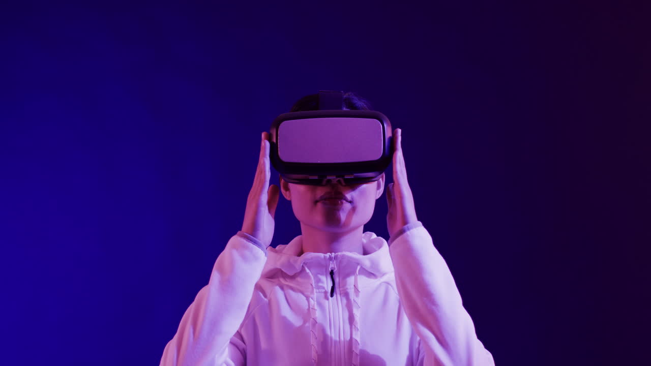 Asian woman using vr headset on blue background, copy space, slow motion