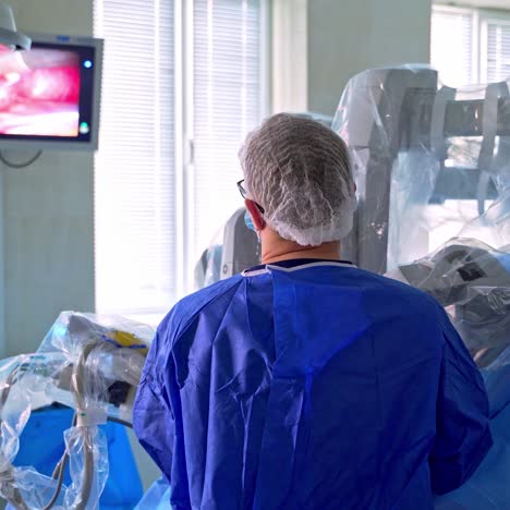 doctor controls the robotic surgery. monitor shows medical procedure. medical operation involving robot. minimally invasive robotic surgery with da vinci.