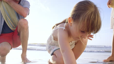 happy family playing on the beach girl drawing in the sand at sunset