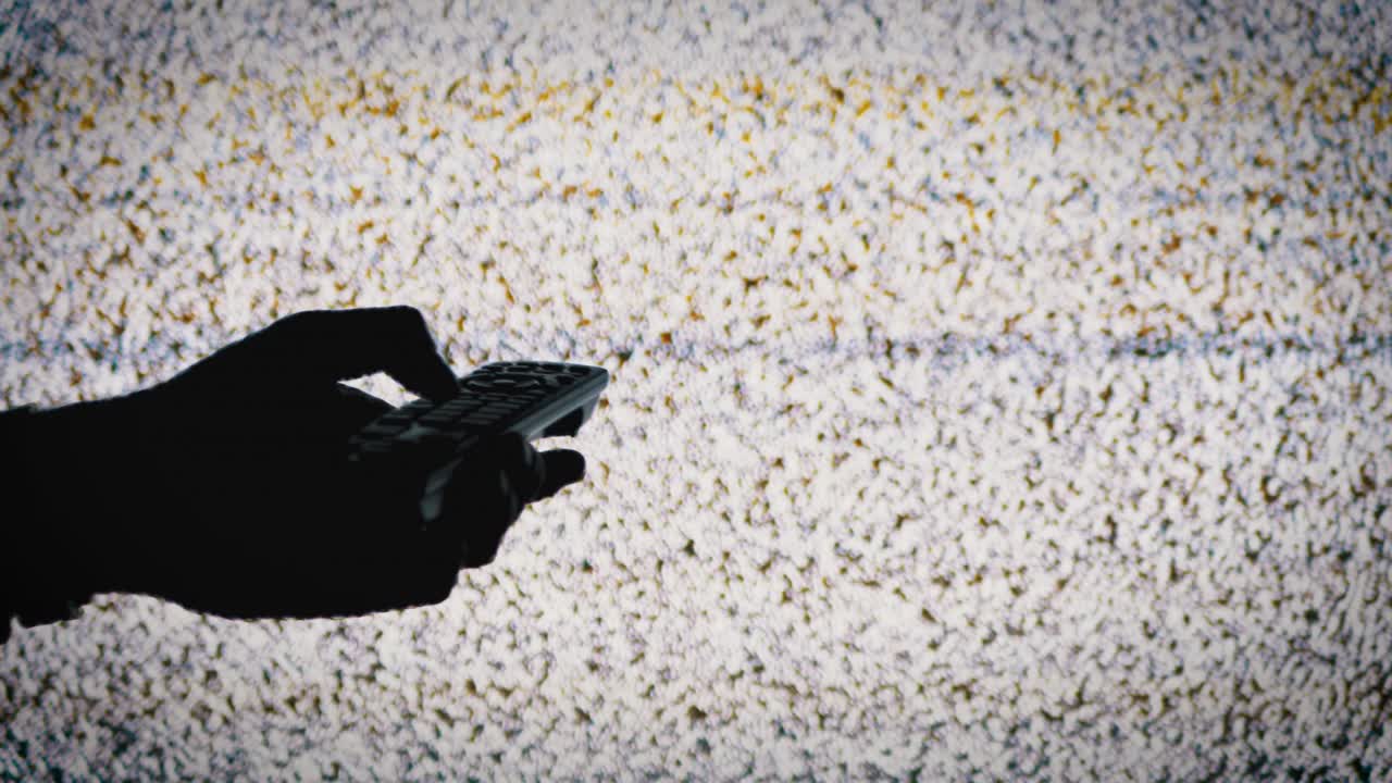 silueta de una mano sosteniendo un control remoto de tv en el fondo de la pantalla de tv con ruido estático blanco