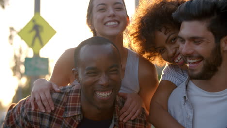 two happy young adult couples piggybacking the street