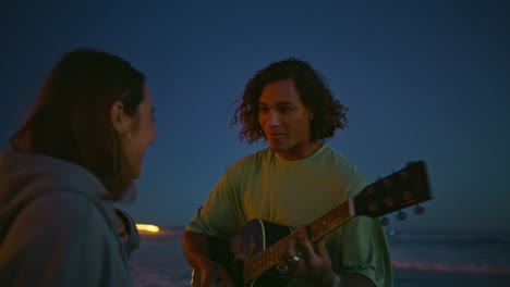 melomaniac pair dating night beach closeup. man playing guitar woman enjoying