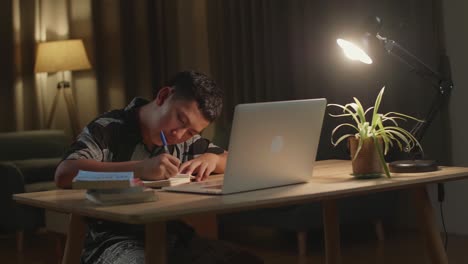 teenage boy learning online from laptop at night