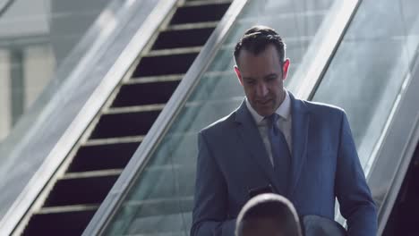 Geschäftsmann-Benutzt-Mobiltelefon-Auf-Rolltreppe-In-Einem-Modernen-Büro-4k