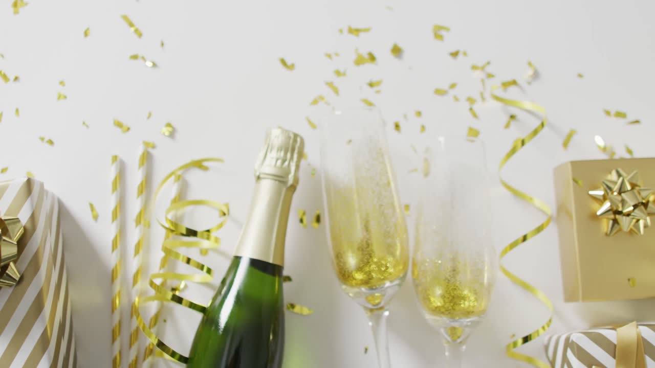 Video di bottiglia di champagne, bicchieri e regali con stelle filanti dorate e coriandoli su bianco