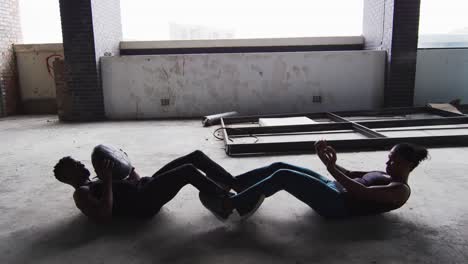 hombre y mujer afroamericanos haciendo ejercicio con una pelota de medicina en un edificio urbano vacío