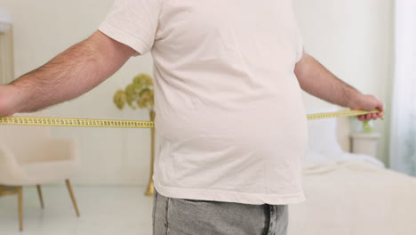 Unrecognizable-Boy-Measuring-His-Waist-In-The-Bedroom-1