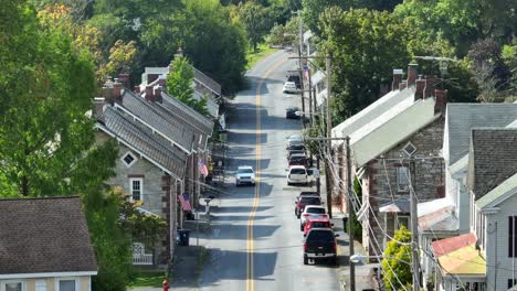 Hillside-street-with-stone-houses-and-parked-cars,-American-flags-displayed