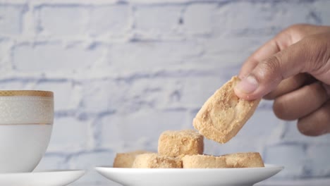 la mano recogiendo una galleta con una taza de té