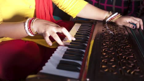 unrecognizable married indian woman playing music with harmonium, close up shot of hands, slow dolly shot