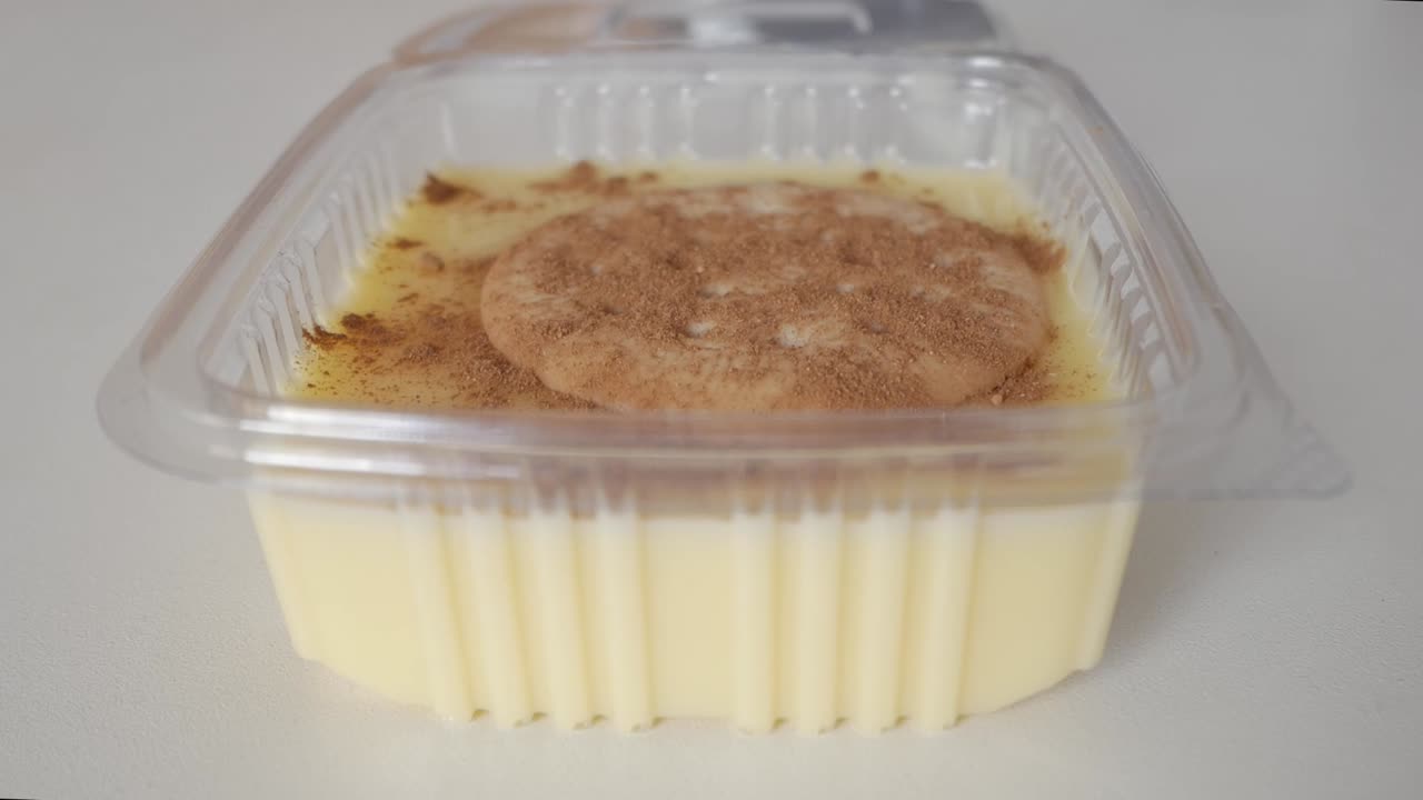 Creamy Spanish natillas with Maria biscuit being garnished with cinnamon on top