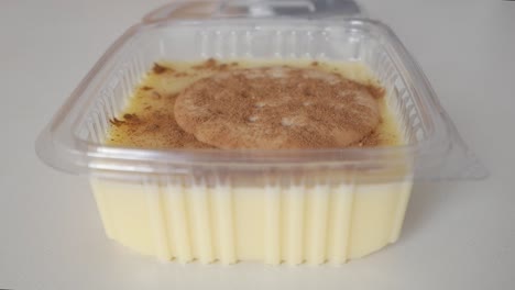 creamy spanish natillas with maria biscuit being garnished with cinnamon on top