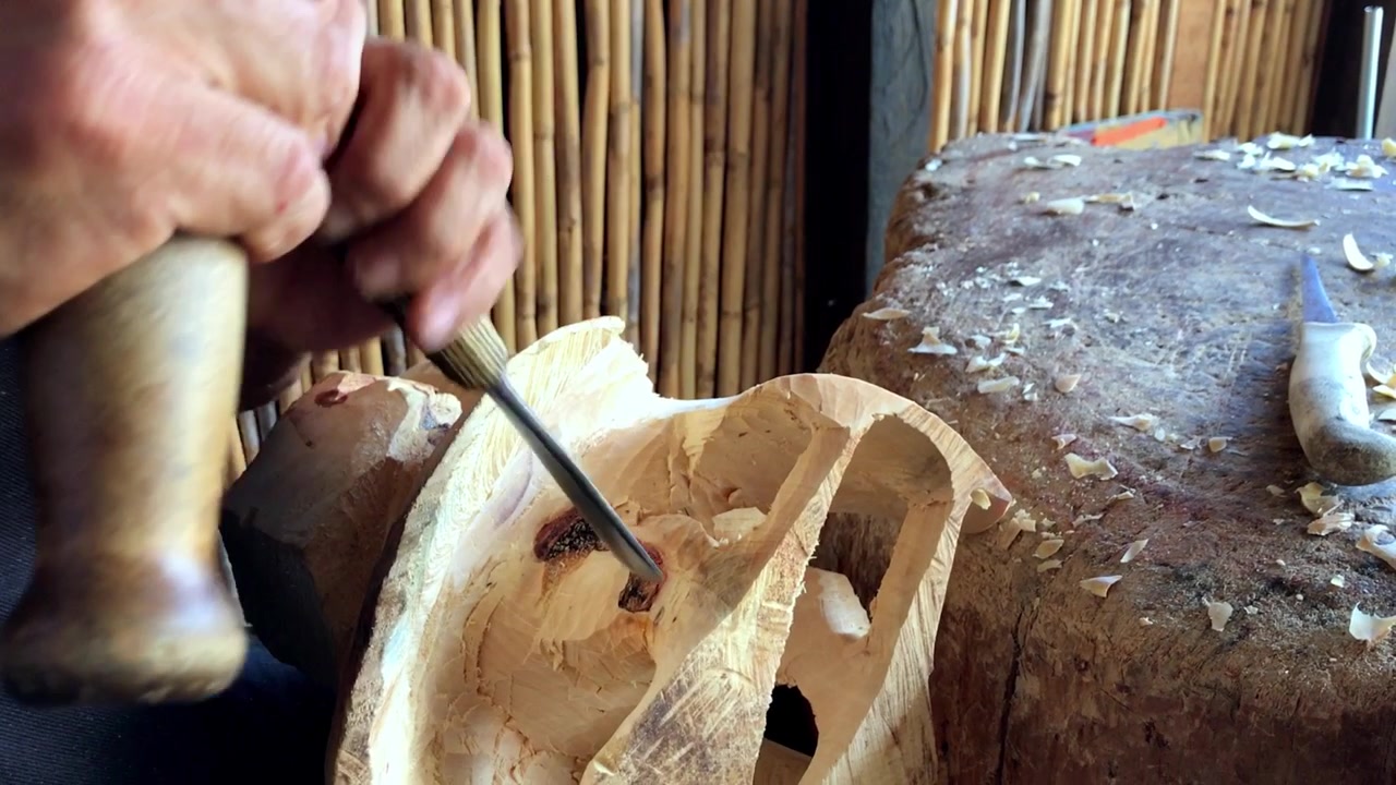 Close view of artisan carving wooden sculpture with hand tools and detailed craftsmanship inside rustic traditional workshop in Mexico