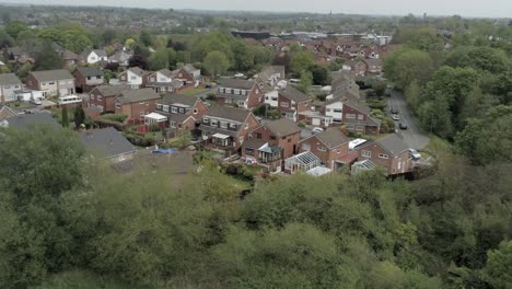 Quiet-British-homes-and-gardens-residential-suburban-property-aerial-view-descend-to-trees