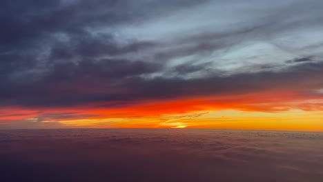 impresionante amanecer de fuego visto desde la cabina de un avión que vuela a través de un cielo bíblico al amanecer, volando bajo las nubes y sobre el mar