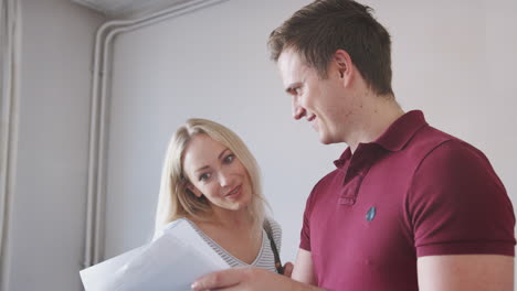 couple buying house for first time looking at house survey in room to be renovated