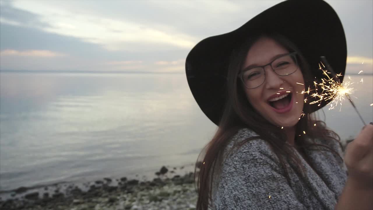 Woman with sparklers at the beach sunset