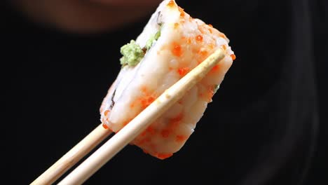 closeup of sushi roll being eaten with chopsticks