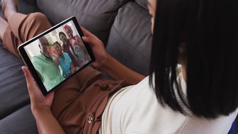 Mujer-Afroamericana-Haciendo-Una-Videollamada-En-Una-Tableta-Digital-Mientras-Está-Sentada-En-El-Sofá-De-Casa