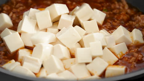 cocinar tofu mapo. freír tofu con salsa picante caliente en una olla en casa.