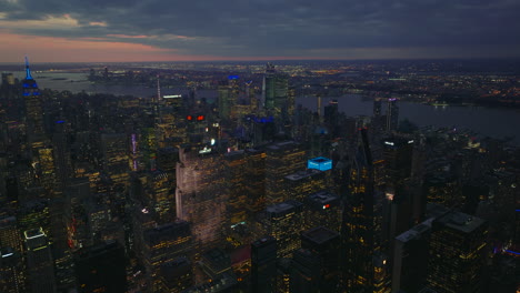 Aerial-panoramic-footage-of-downtown-high-rise-buildings-in-large-city-at-twilight.-Lighted-windows-and-colourful-rooftops-of-skyscrapers.-Manhattan,-New-York-City,-USA