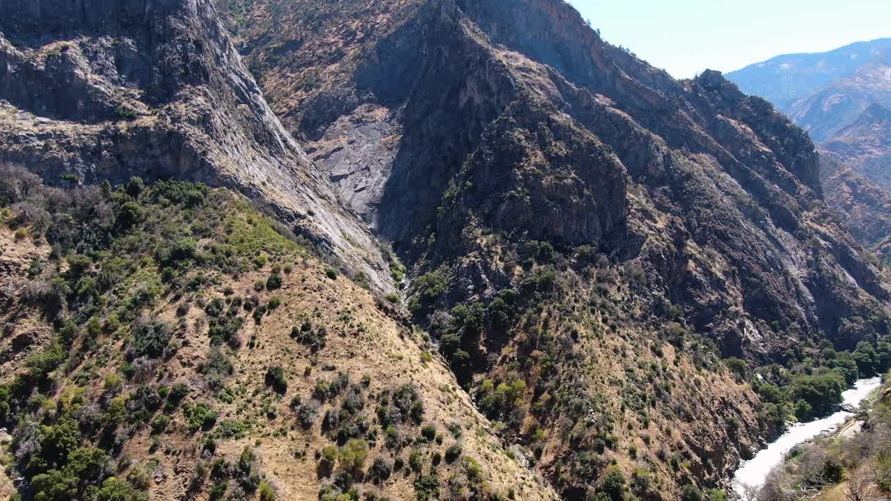 Aerial shot over Kings Canyon majestic hills, verdant trees, and the Kings River in the backdrop, bathed in California's brilliant sunlight