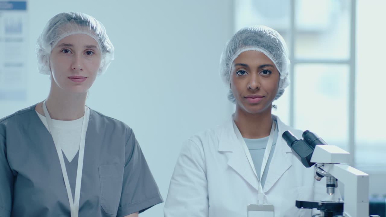 Portrait of Two Female Scientists with Microscope at Work in Laboratory
