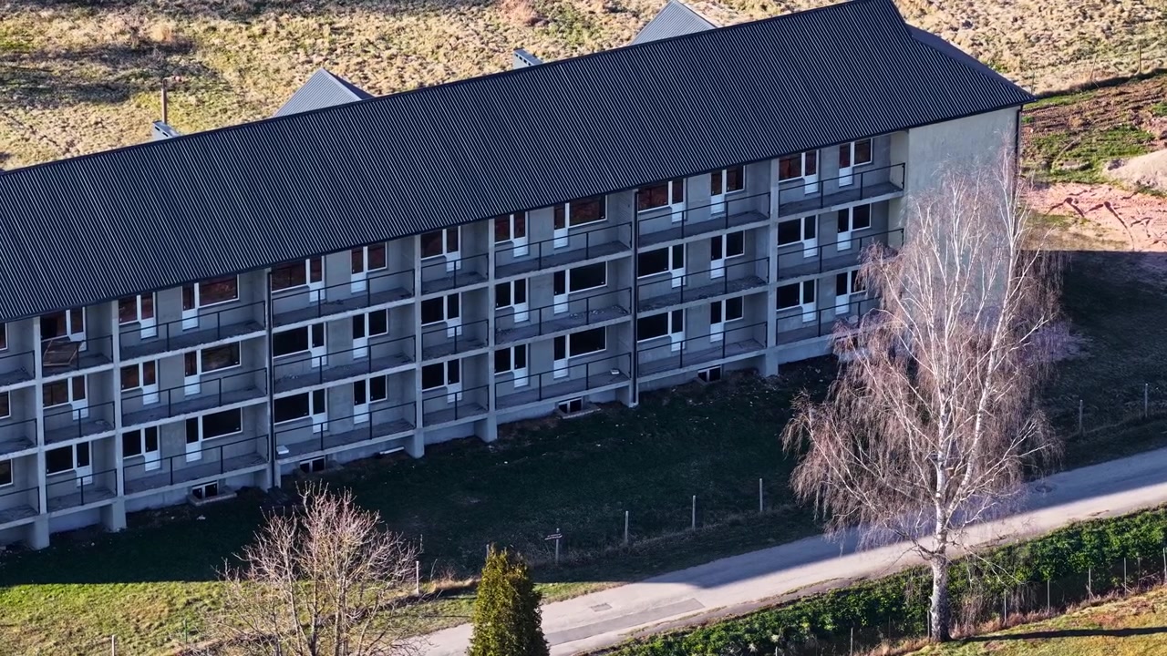 Drone view circling a desolate and derelict multi story housing block in a rural area