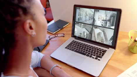 African-american-woman-watching-home-cctv-camera-views-on-laptop,-slow-motion