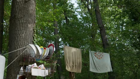 off grid kitchen camp scene linen and crockery hang from trees pan down shot