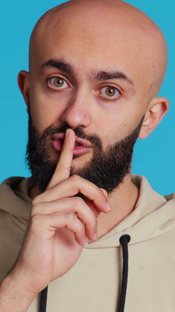 Vertical Video Middle eastern man doing hush silence symbol in studio