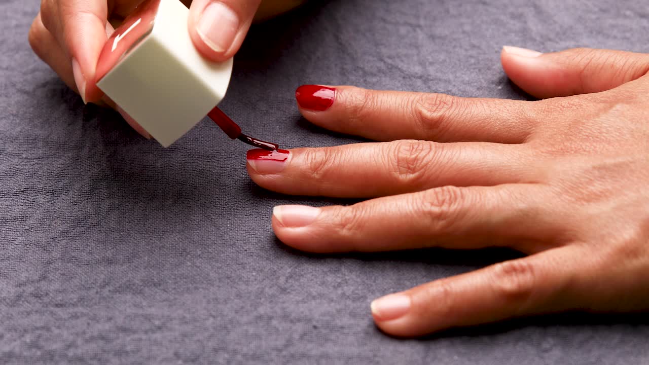 mujer pintándose las uñas con esmalte de uñas rojo