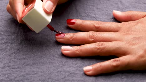 woman painting her nails with red nail polish